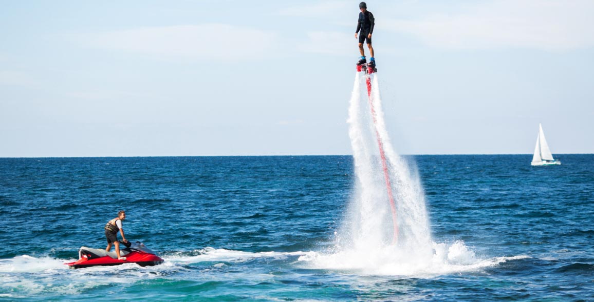 Мальчик летит, как супергерой, занимается водными видами спорта на флайборде в Дубае